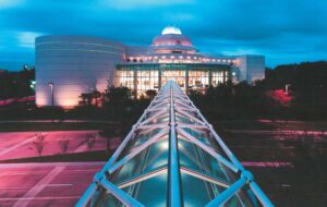 night exterior of building with skywalk and observatory dome at orlando science center
