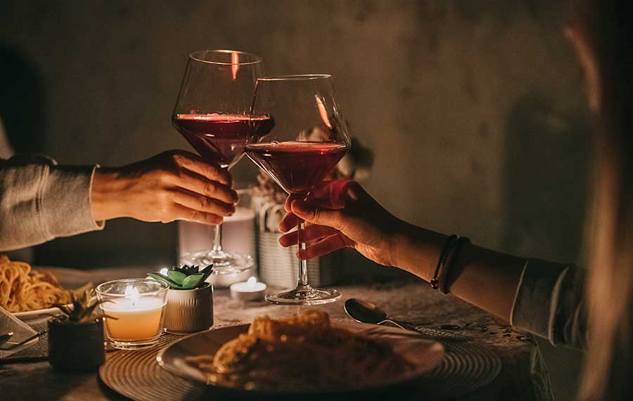 romantic candlelight dinner for two toasting wine glasses