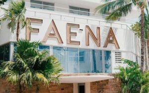 sign on exterior with blue windows palms and balconies at faena hotel miami beach