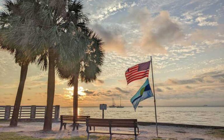 sunrise cloudy sky with park benches palm trees and flags at bill baggs cape florida state park miami