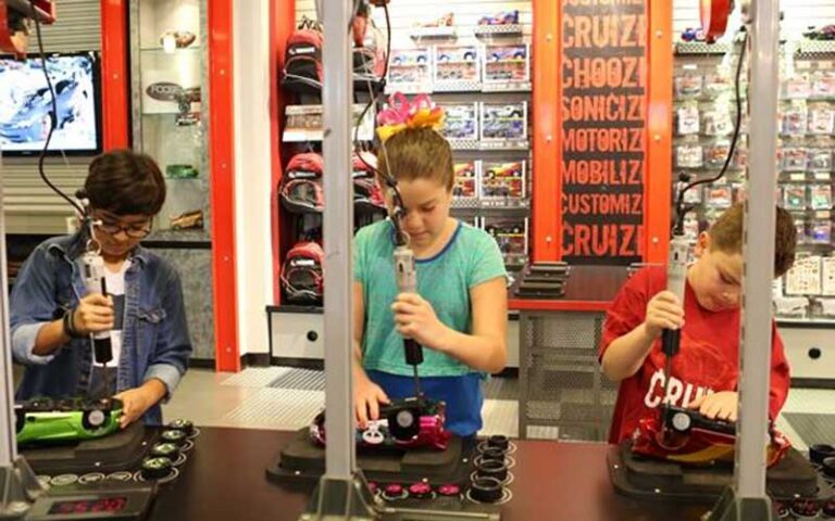 two boys and a girl assembling toy cars on shop tool benches at ridemakerz store orlando