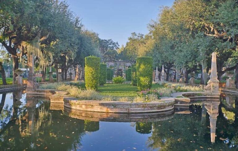 view across pool of garden with hedges and trees at vizcaya museum gardens miami