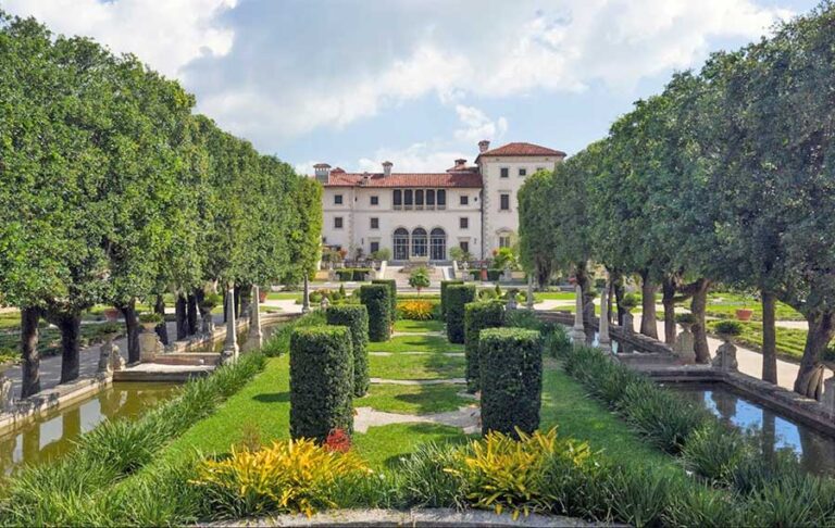 view over garden with rows of boxed hedges and mansion centered at vizcaya museum gardens miami