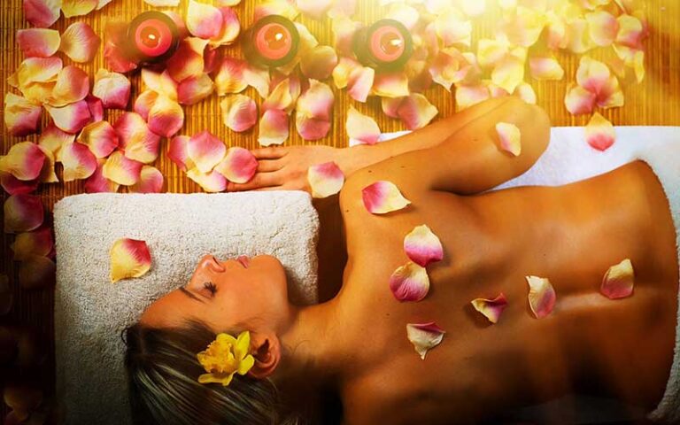 woman lying on massage table with petals and candles on side at wild berry tea spa jacksonville