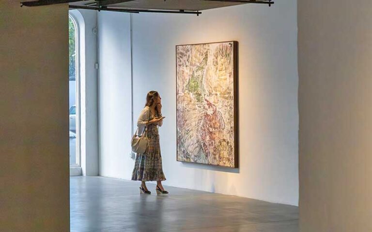 woman viewing art on exhibit wall with window at perez art museum miami