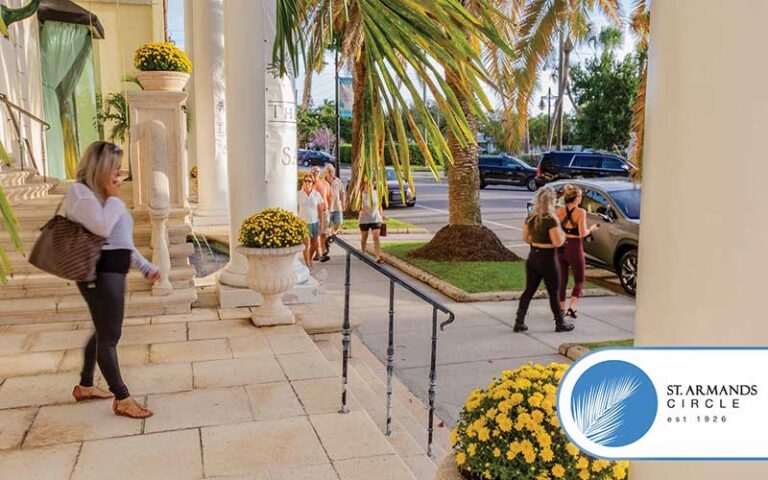 woman with bag talking on phone and walking down steps at building with columns at st armands circle sarasota