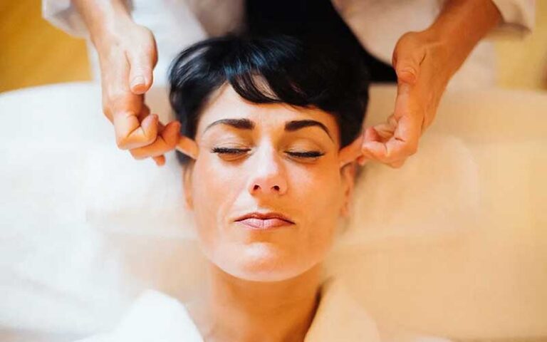 woman with long black hair in robe having temples massaged at wild berry tea spa jacksonville