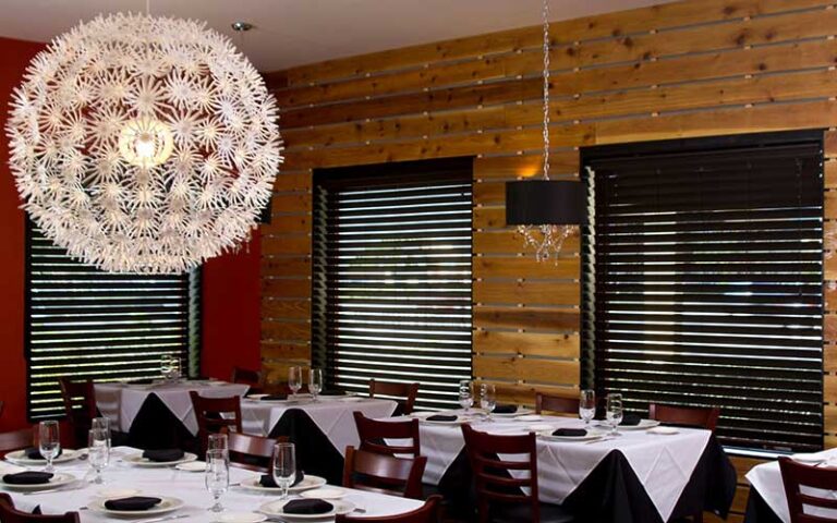 dining room interior with wood panel and white globe pendant at antoines restaurant sarasota