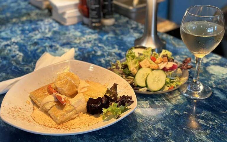 entree and salad with wine on blue tabletop at lobster pot sarasota