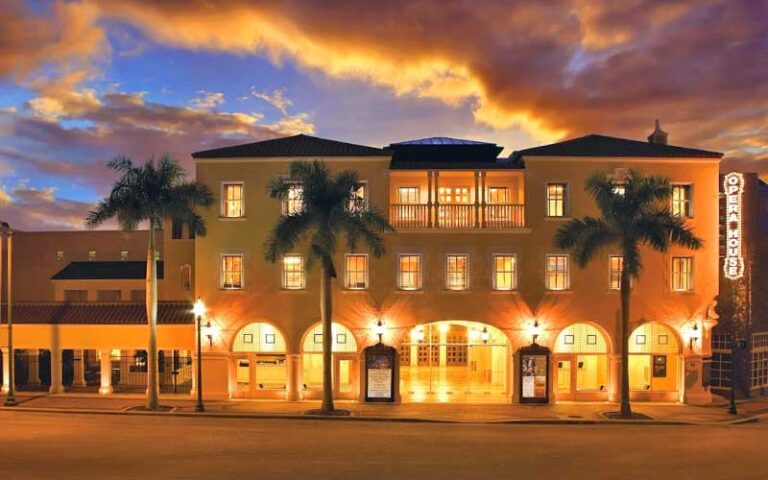 front exterior of theater with gold lighting at night and dusk clouds at sarasota opera house