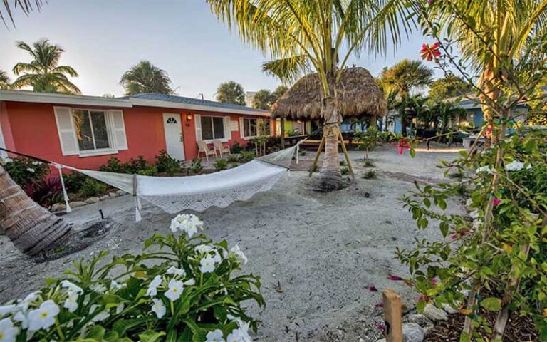 outdoor patio area with palms and hammock behind coral colored villa at siesta key beachside villas sarasota