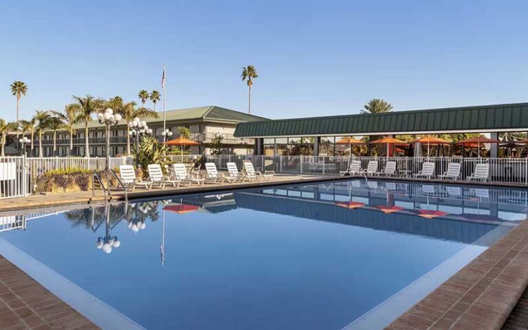 pool with rows of chairs and hotel behind at ramada by wyndham sarasota waterfront
