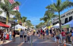 street lined with shops booths and palm trees at sarasota farmers market