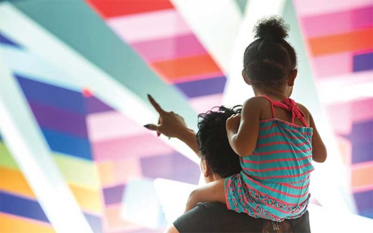 toddler on dads shoulders looking at colorful art at moca museum of contemporary art jacksonville