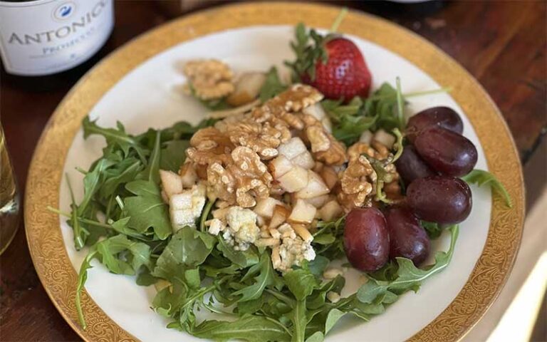 waldorf salad with grapes and strawberries on plate with wine bottle at garden room cafe at shoogie boogies sarasota