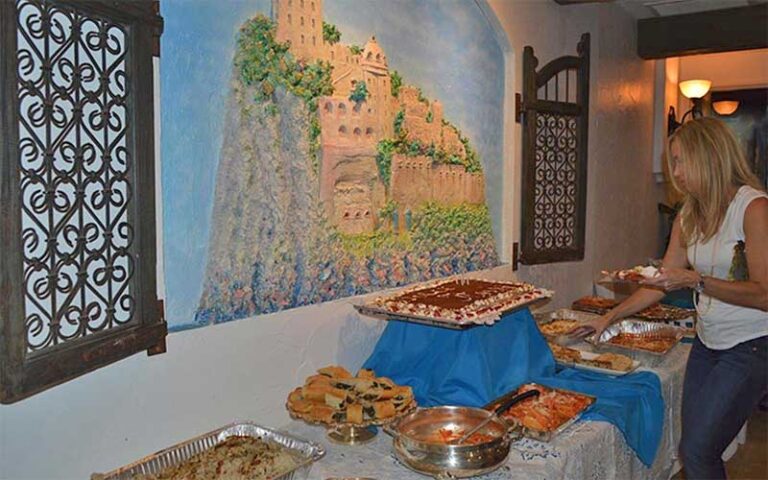 woman serves herself at buffet table with pastas and wall murals at dolce italia sarasota