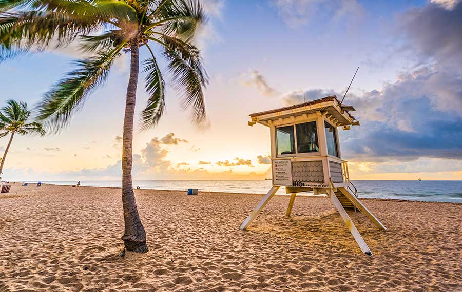 fort lauderdale beach with low sun through clouds palm trees and lifeguard shack