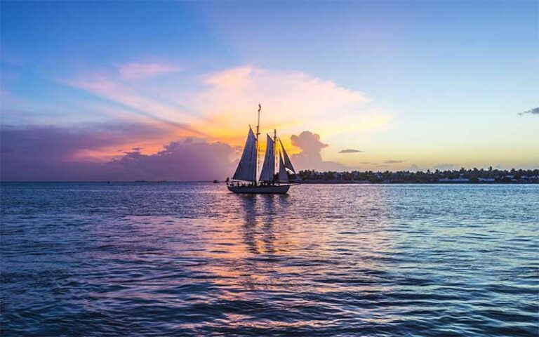 colorful sunset over water with sailboat at key west historic seaport