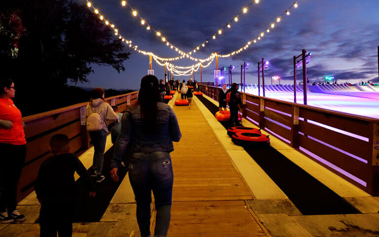 conveyor belt sending snow tubes uphill with lit up walkway at snowcat ridge dade city