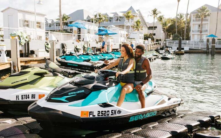 couple on jet ski with hotel marina at opal key resort marina key west