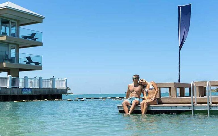 couple on swim dock with pier hotel and water at pier house resort spa key west