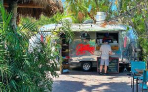 food trailer in courtyard area with shady trees and customer ordering at garbos grill key west