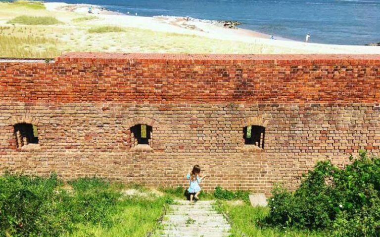red brick fortress wall on beach with girl at fort clinch state park jacksonville