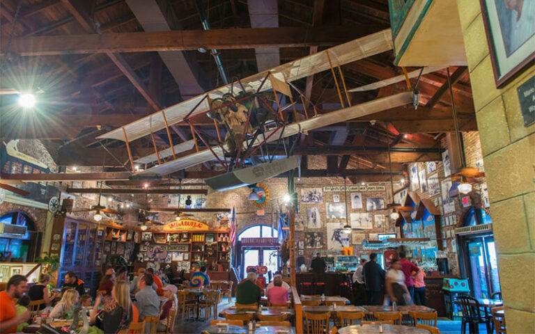 restaurant interior dining area with antique airplane hanging in rafters at el meson de pepe key west