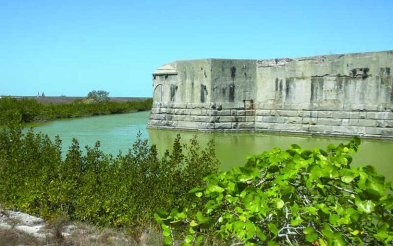 stone fortress with moat and shrubs along wall at fort zachary taylor historic state park key west