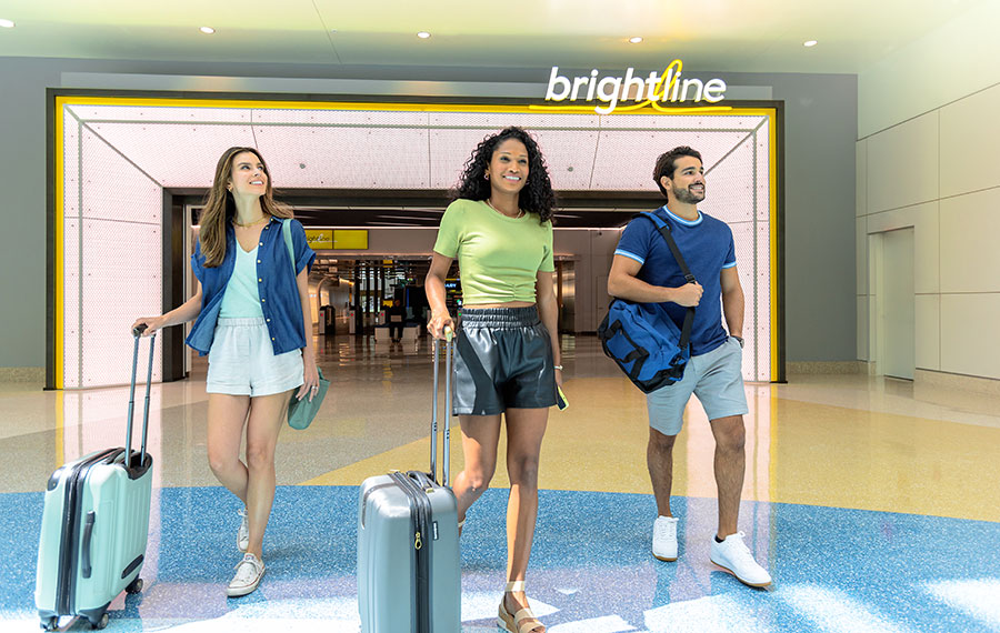 travelers with luggage enter train station at airport brightline station
