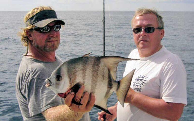 two fishermen on boat holding up large spadefish at historic charter boat row key west