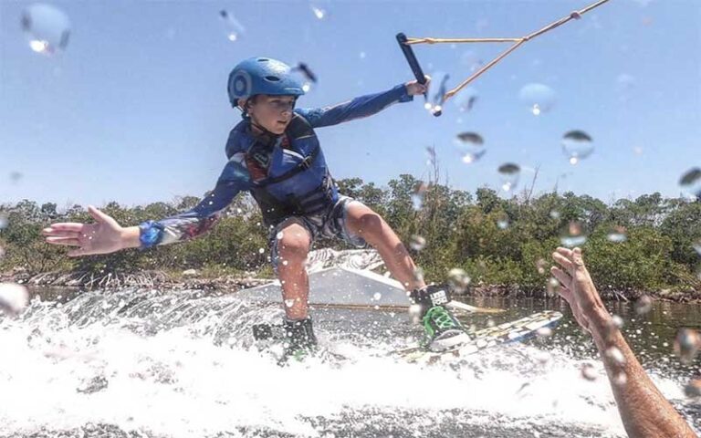 boy wakeboarding past trainer giving high five at keys cable park marathon
