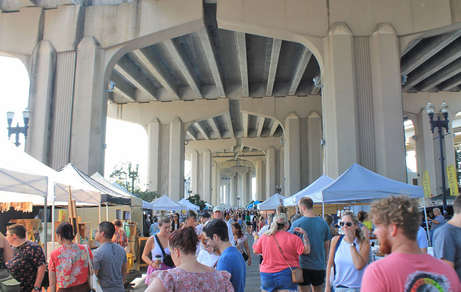 bustling outdoor market with huge bridge pilings riverside arts market jacksonville