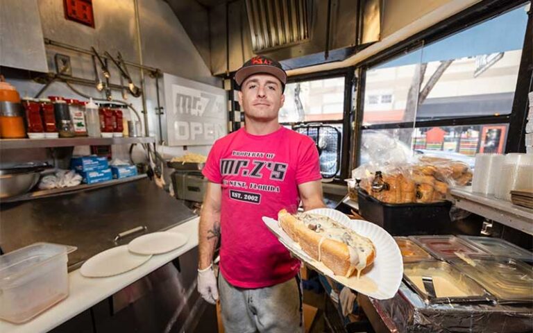 chef in red shirt holding out cheesesteak at mr zs key west