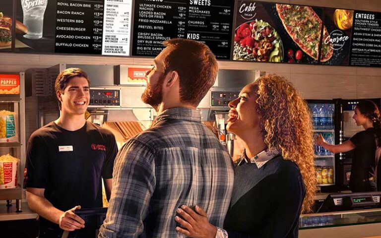 couple at counter ordering food with menu board at amc dine in coral ridge mall ft lauderdale