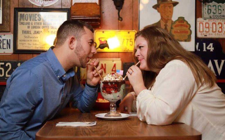 couple sharing an ice cream float at dining table with memorabilia at jaxsons ice cream parlor fort lauderdale