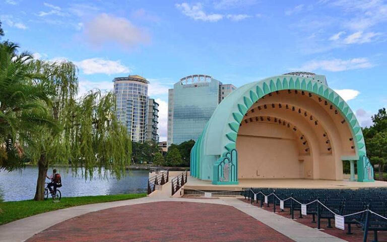 disney amphitheater along water with biker and trees at lake eola park orlando