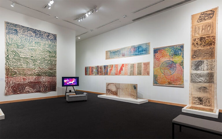 exhibit room with tapestry art and benches at boca raton museum of art