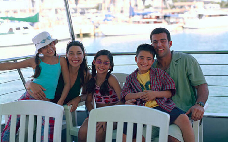 family smiling seated in chairs on deck of boat with marina at st johns river taxi jacksonville