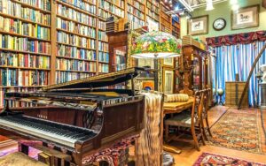 grand piano and tiffany lamp with bookshelves at old florida book shop fort lauderdale
