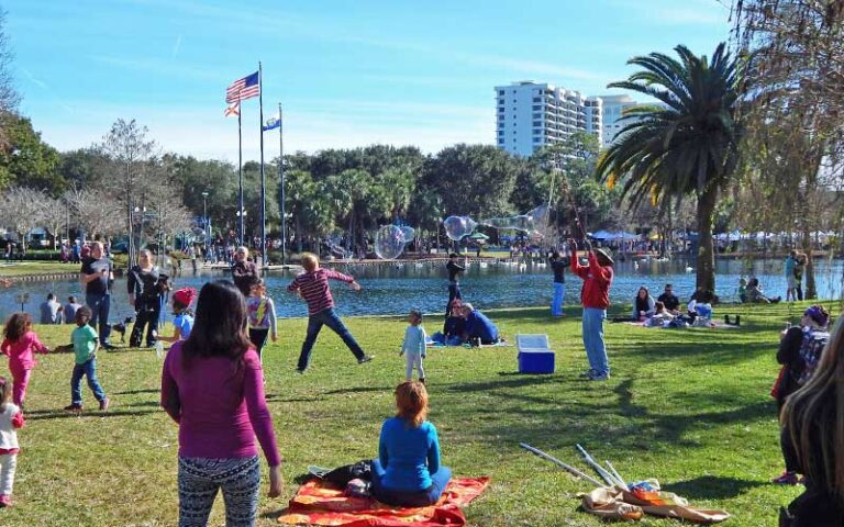 grassy play area of park with bubble maker and families at lake eola park orlando