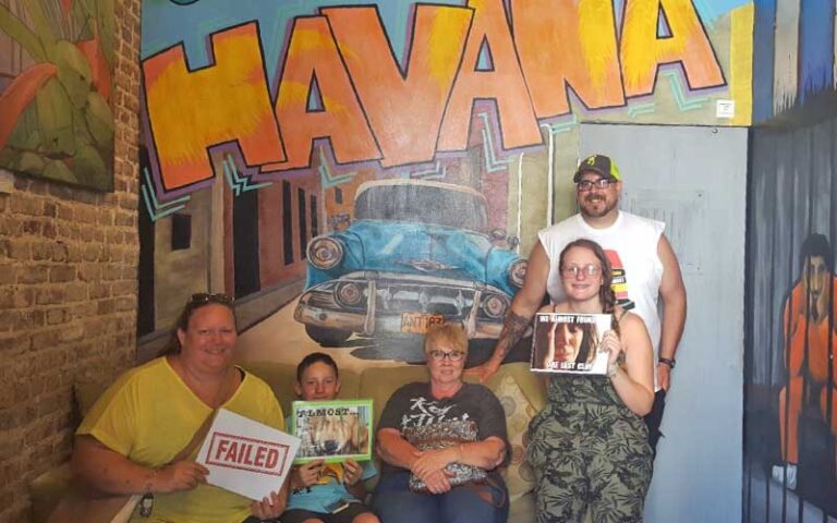 group posing in front of havana mural at key west room escape