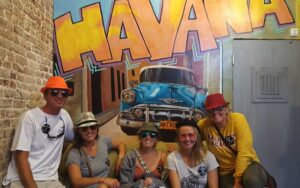 group with hats posing under havana mural at key west room escape