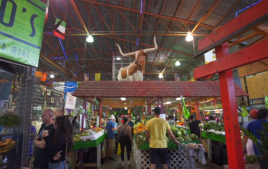 indoor flea market with stalls of produce and steer statue at yellow green farmers market
