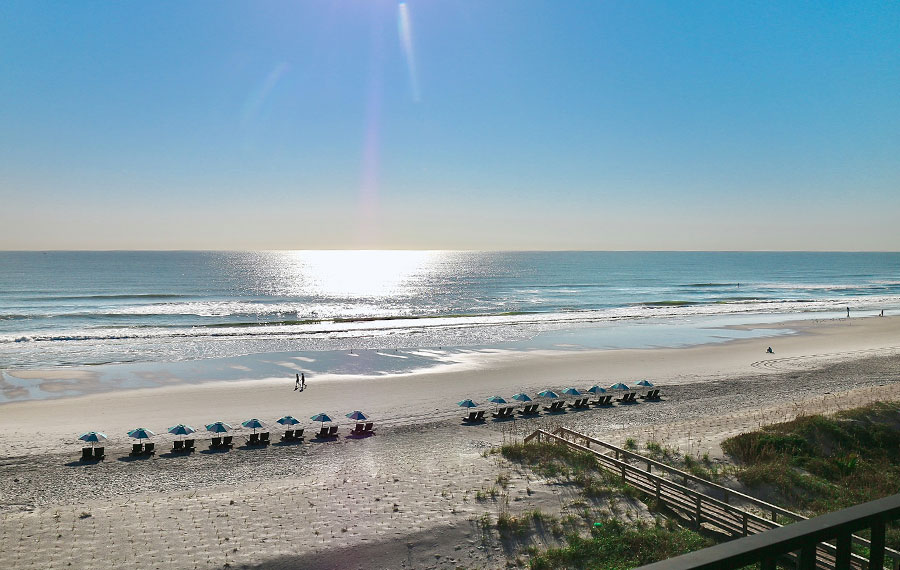 low sun over beach with clear sky rows of chairs and people walking one ocean resort atlantic beach