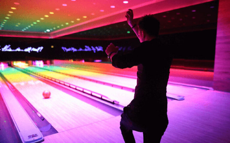 man throwing ball down bowling lane with rainbow lighting at basement bowl and skate miami beach edition