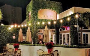 night exterior of restaurant with ivy framed sign and patio diners at bijou garden cafe sarasota