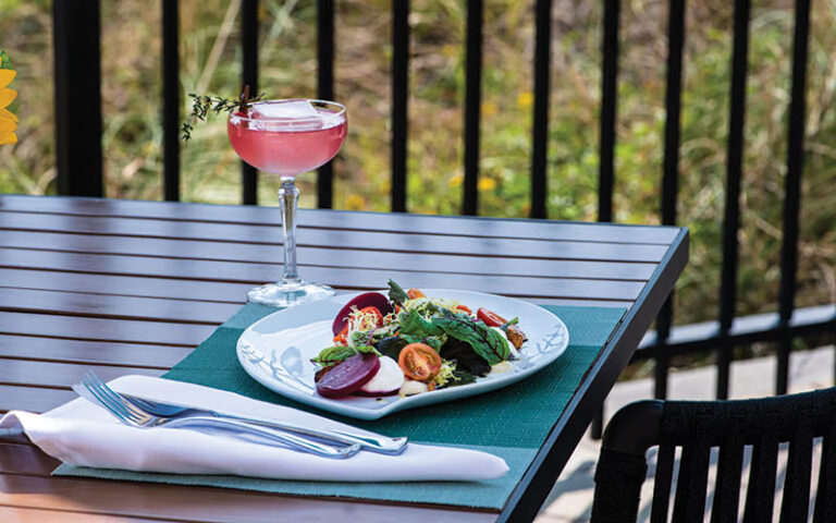 outdoor dining table with pink cocktail and salad at azurea at one ocean jacksonville