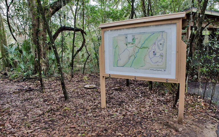 placard with posted map of trails in wooded area at tree hill nature center jacksonville