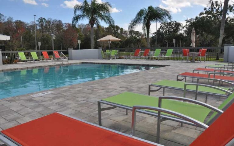 pool area with palms and colorful lounge chairs at grand hotel kissimmee